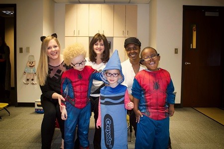 An image of three women posing with costumed children from the Center for the Visually Impaired