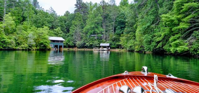 An image of the bow of a boat looking out over a lake & forest